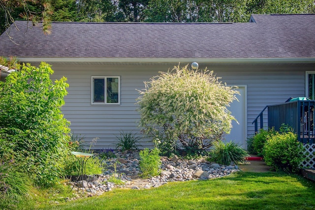 view of side of home with a yard and roof with shingles