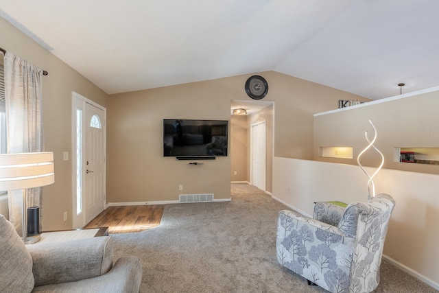 living area featuring carpet, visible vents, vaulted ceiling, and baseboards