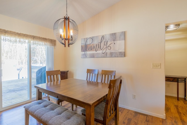 dining room featuring baseboards, a chandelier, vaulted ceiling, and wood finished floors