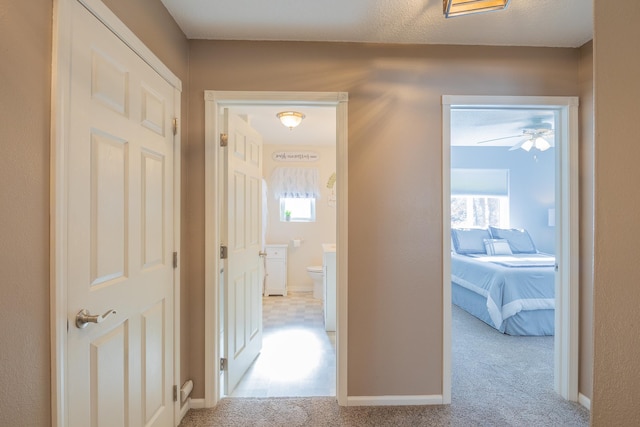 hall with a wealth of natural light, carpet flooring, and baseboards