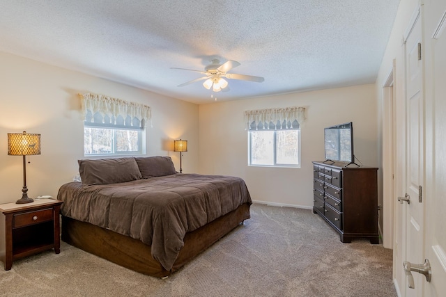 bedroom featuring multiple windows, a ceiling fan, a textured ceiling, and light colored carpet