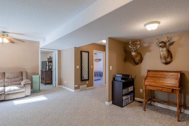 interior space with light carpet, baseboards, visible vents, a ceiling fan, and a textured ceiling