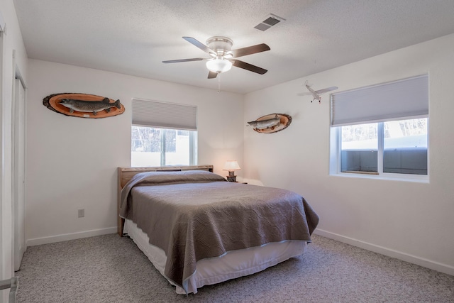 carpeted bedroom featuring a textured ceiling, ceiling fan, visible vents, and baseboards