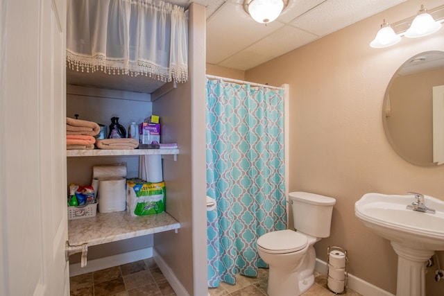 bathroom featuring a shower with shower curtain, baseboards, and toilet