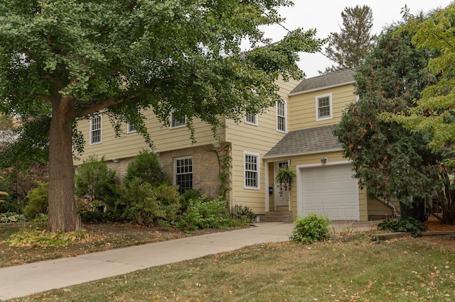 view of front of house with stone siding, concrete driveway, roof with shingles, and an attached garage