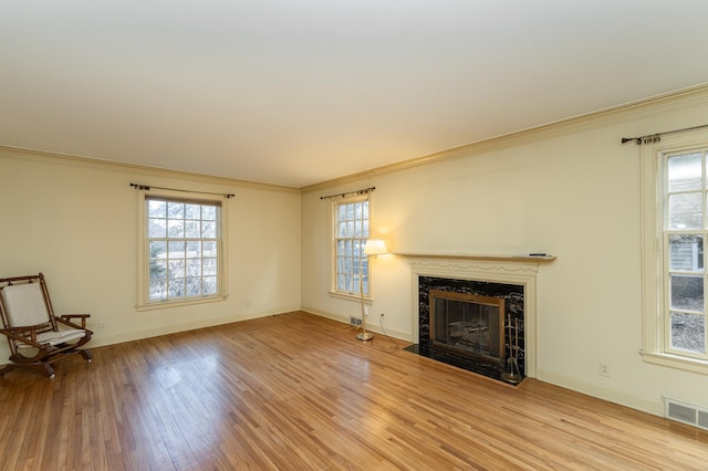 unfurnished living room with a healthy amount of sunlight, a fireplace, visible vents, and light wood-style floors