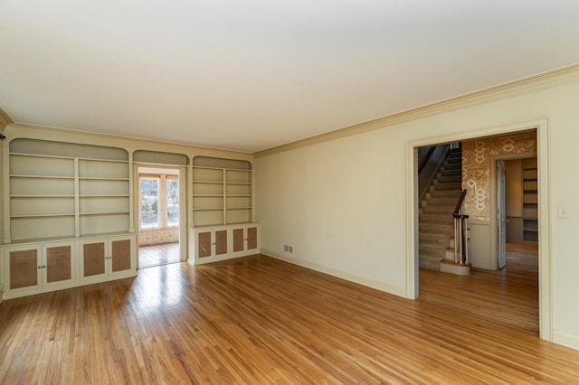 spare room with stairs, ornamental molding, wood finished floors, and baseboards