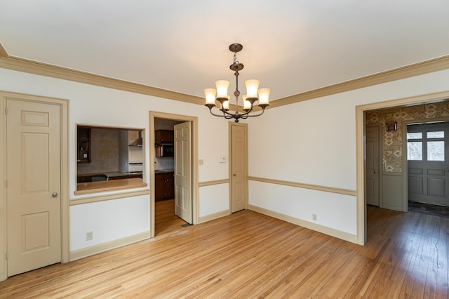 empty room with light wood-type flooring, baseboards, a chandelier, and crown molding