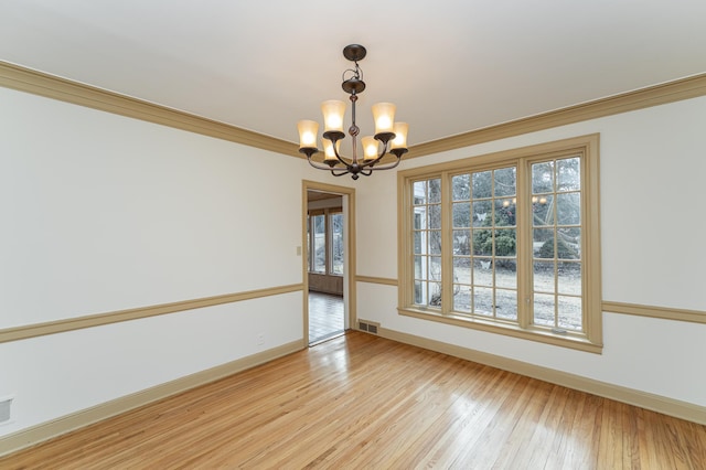 spare room with visible vents, light wood-style flooring, ornamental molding, a chandelier, and baseboards