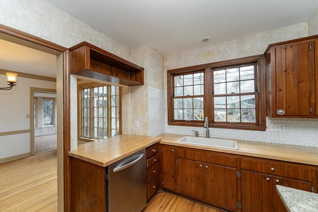 kitchen with stainless steel dishwasher, plenty of natural light, a sink, and light wood-style flooring