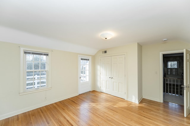 unfurnished bedroom featuring light wood finished floors, visible vents, vaulted ceiling, and a closet