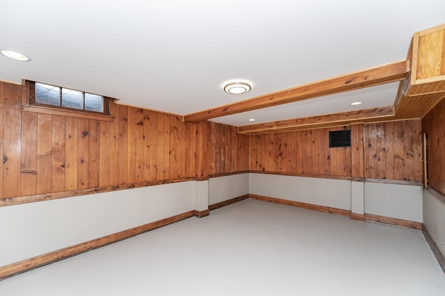 basement featuring wooden walls, baseboards, and recessed lighting