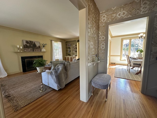1130 6th St SW, Rochester, MN 55902 - living area featuring wood finished floors, a chandelier, a glass covered fireplace, baseboards, and crown molding