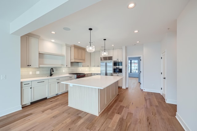 kitchen featuring high end appliances, tasteful backsplash, decorative light fixtures, a center island, and light wood-type flooring