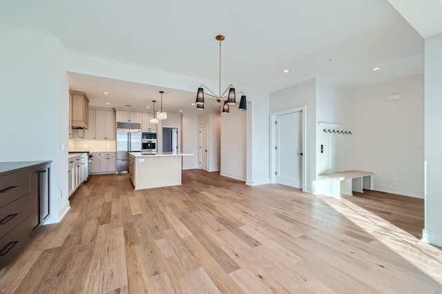 kitchen with pendant lighting, stainless steel built in refrigerator, a kitchen island, and light hardwood / wood-style flooring