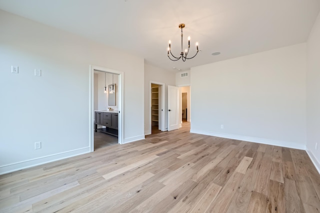 interior space with a closet, a walk in closet, an inviting chandelier, and light hardwood / wood-style floors