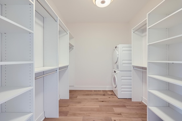 walk in closet with stacked washer / dryer and light hardwood / wood-style flooring