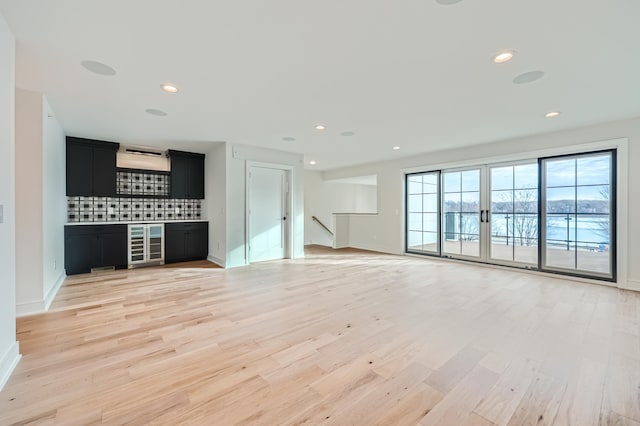 unfurnished living room with indoor bar, beverage cooler, and light wood-type flooring