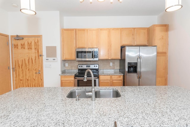 kitchen with sink, appliances with stainless steel finishes, tasteful backsplash, light stone countertops, and light brown cabinetry