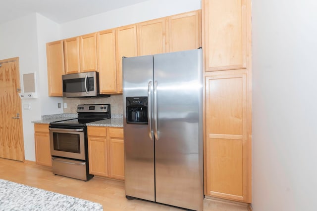 kitchen with light brown cabinets, light hardwood / wood-style flooring, light stone countertops, and appliances with stainless steel finishes