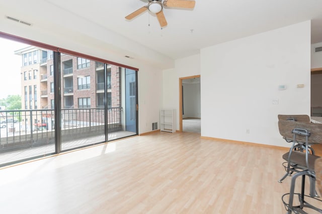 empty room with ceiling fan and light hardwood / wood-style flooring