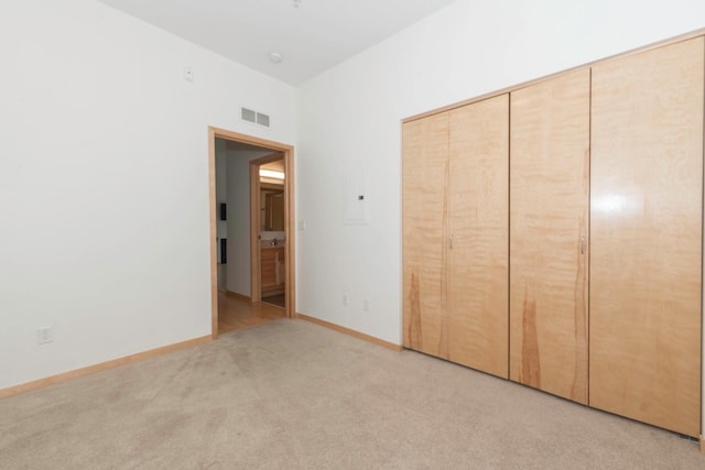 unfurnished bedroom featuring light carpet and a closet