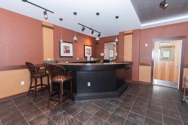 bar with dark tile patterned floors, track lighting, and decorative light fixtures