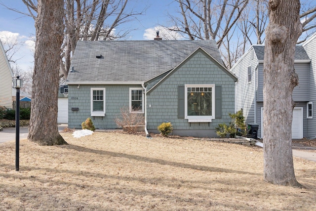 view of front facade featuring a chimney and a shingled roof