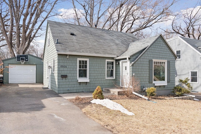 view of front of home with a garage, an outbuilding, roof with shingles, and driveway