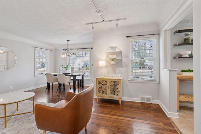 living room featuring a notable chandelier, visible vents, wood-type flooring, and a textured ceiling