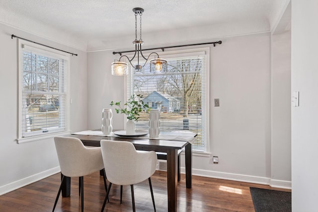 dining space with baseboards, a textured ceiling, a chandelier, and dark wood finished floors