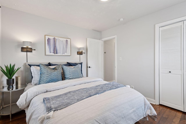 bedroom with a closet, baseboards, and dark wood-type flooring