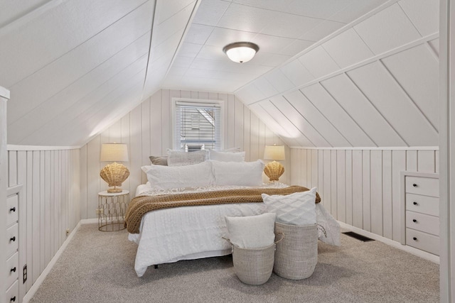 bedroom featuring visible vents, wood walls, lofted ceiling, and carpet