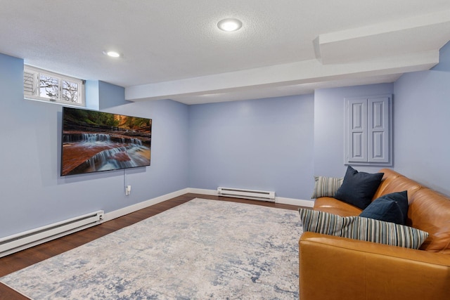 living area with a textured ceiling, a baseboard heating unit, baseboards, and wood finished floors