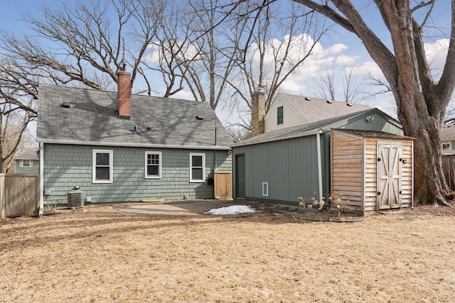 rear view of house featuring a patio, fence, central AC, a chimney, and an outdoor structure