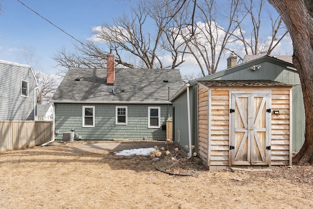 back of property with an outbuilding, a storage unit, a chimney, and central AC