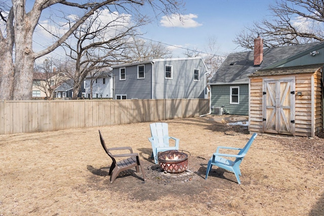 view of yard with fence, an outdoor fire pit, an outdoor structure, a storage shed, and central air condition unit