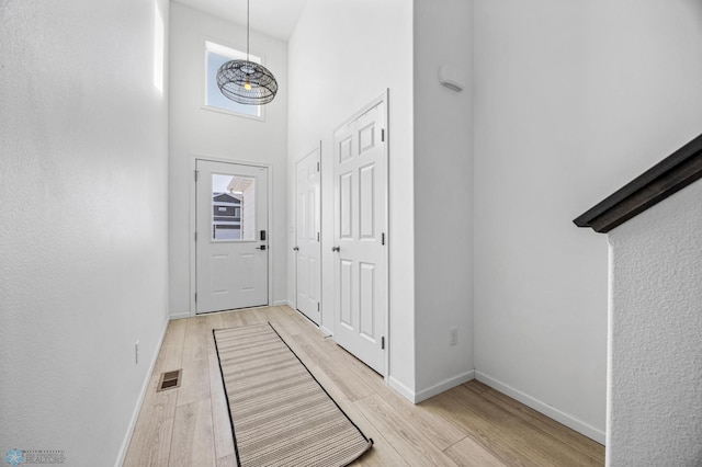 doorway featuring a towering ceiling and light wood-type flooring