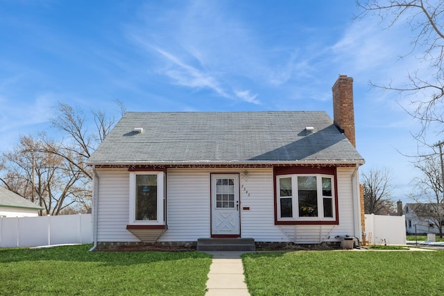 view of front of property featuring a front yard, fence, roof with shingles, and a chimney