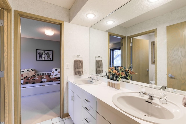 bathroom featuring double vanity, tile patterned flooring, a sink, and toilet