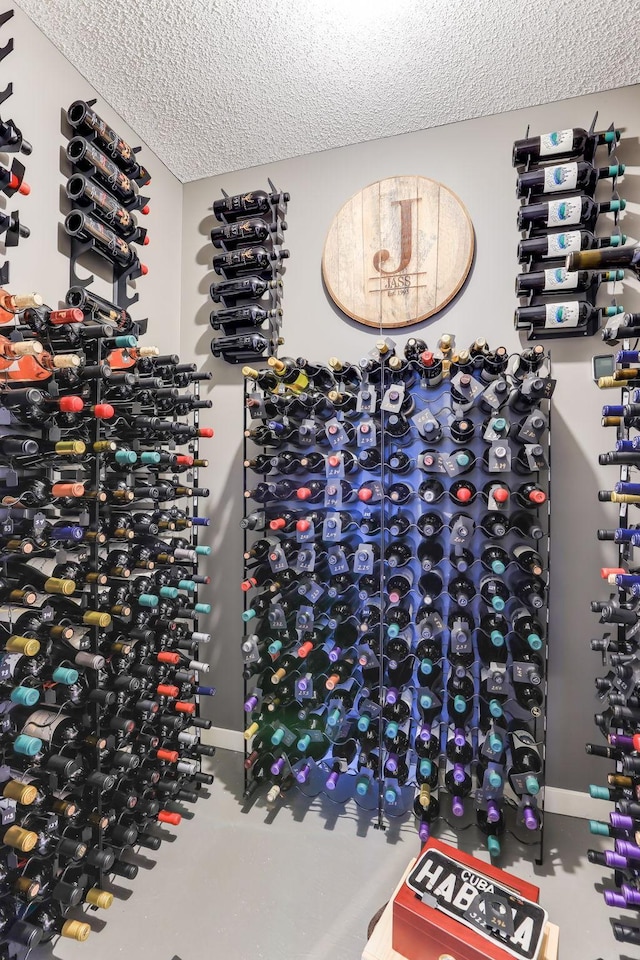 wine room with baseboards, concrete flooring, and a textured ceiling