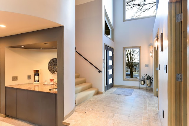 foyer featuring a healthy amount of sunlight, a towering ceiling, stairway, and recessed lighting