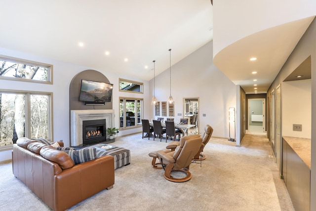 living room with light carpet, recessed lighting, high vaulted ceiling, and a glass covered fireplace