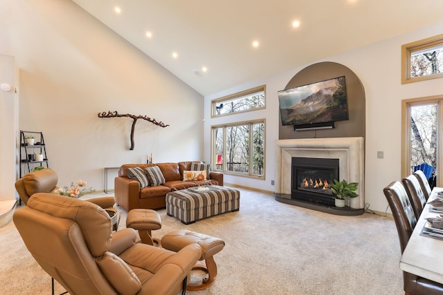 living room with high vaulted ceiling, carpet, a glass covered fireplace, and plenty of natural light