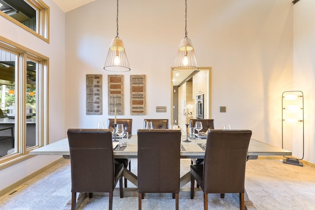 dining room with carpet, visible vents, and a towering ceiling