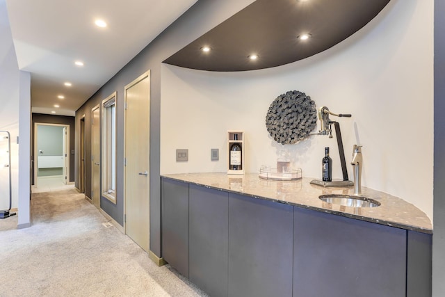 hallway featuring light carpet, baseboards, a sink, and recessed lighting