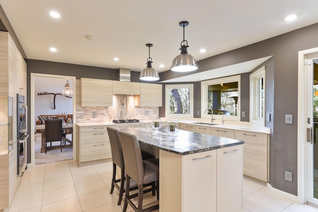 kitchen featuring tasteful backsplash, modern cabinets, a kitchen island, appliances with stainless steel finishes, and a sink