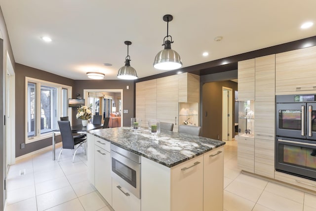 kitchen with dobule oven black, stainless steel microwave, and modern cabinets