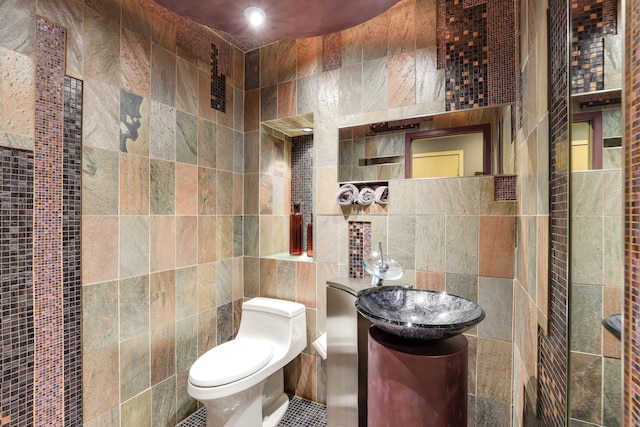 half bathroom with toilet, tasteful backsplash, tile walls, and vanity