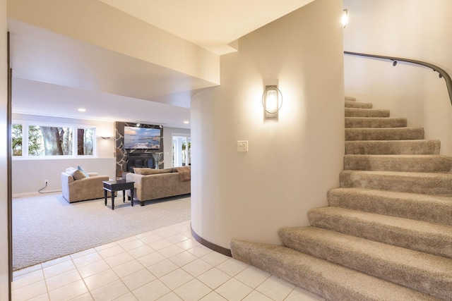 stairway with a healthy amount of sunlight, carpet, a fireplace, and tile patterned floors